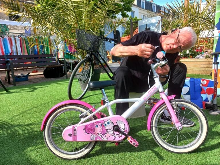 Bénévole réparant un vélo d’enfant rose